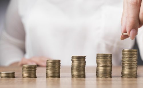 woman-placing-coin-pile-coins.jpg